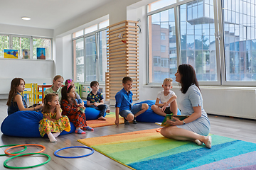 Image showing Reading time in an elementary school or kindergarten, a teacher reads a book to children in an elementary school or kindergarten. The concept of pre-school education. Selective focus