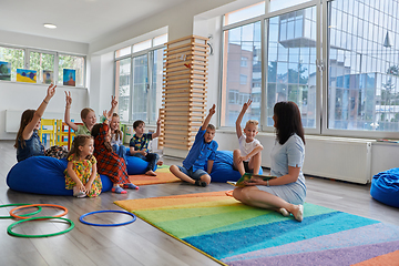 Image showing Reading time in an elementary school or kindergarten, a teacher reads a book to children in an elementary school or kindergarten. The concept of pre-school education. Selective focus