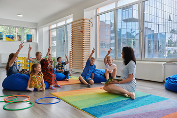 Image showing Reading time in an elementary school or kindergarten, a teacher reads a book to children in an elementary school or kindergarten. The concept of pre-school education. Selective focus