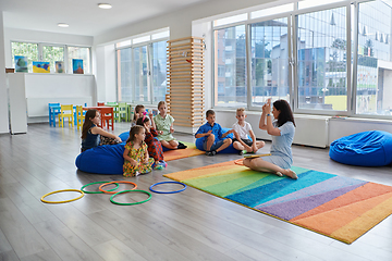 Image showing Reading time in an elementary school or kindergarten, a teacher reads a book to children in an elementary school or kindergarten. The concept of pre-school education. Selective focus