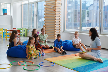 Image showing Reading time in an elementary school or kindergarten, a teacher reads a book to children in an elementary school or kindergarten. The concept of pre-school education. Selective focus