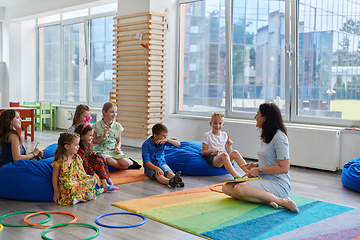 Image showing Reading time in an elementary school or kindergarten, a teacher reads a book to children in an elementary school or kindergarten. The concept of pre-school education. Selective focus