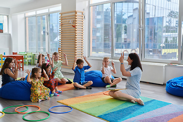 Image showing Reading time in an elementary school or kindergarten, a teacher reads a book to children in an elementary school or kindergarten. The concept of pre-school education. Selective focus