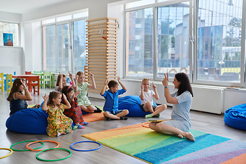 Image showing Reading time in an elementary school or kindergarten, a teacher reads a book to children in an elementary school or kindergarten. The concept of pre-school education. Selective focus