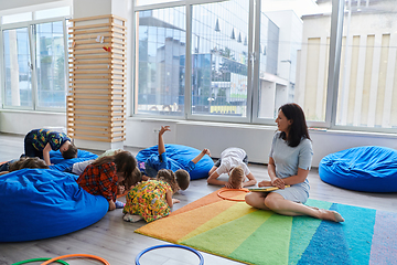 Image showing Reading time in an elementary school or kindergarten, a teacher reads a book to children in an elementary school or kindergarten. The concept of pre-school education. Selective focus