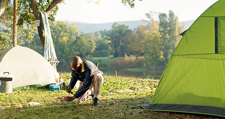 Image showing Camping, tent and black man setup in woods for shelter on outdoor holiday, vacation and adventure, Campsite, traveling and male person with hammer for pins for gear in nature, forest and countryside