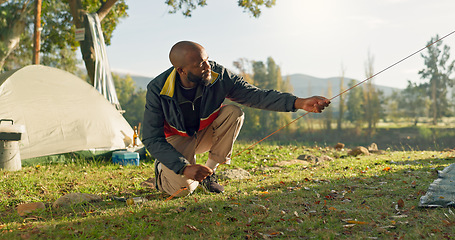 Image showing Camping, tent in ground and black man setup in nature for shelter on outdoor holiday, vacation and adventure, Campsite, travel and male person with hammer for gear in woods, forest and countryside