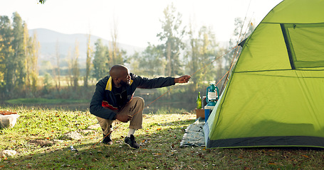 Image showing Camping, tent and black man setup in nature for shelter on outdoor holiday, vacation and adventure, Campsite, traveling and male person with hammer for pins for gear in woods, forest and countryside