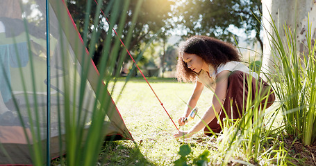 Image showing Tent, nature and woman with a setup for a camp in a forest for holiday or adventure. Vacation, outdoor and a young girl with a hammer for shelter in the woods for a break, trekking or gear in morning