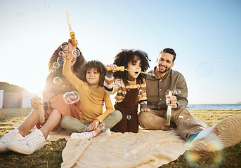 Image showing Bubbles, game and children playing with parents, bonding and fun outdoor, relax on lawn with love and care. Mother, father and girl kids, people playful with liquid soap and summer in nature