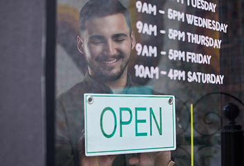 Image showing Shop, window and happy businessman open with sign for working time in retail, store or service in small business. Opening, restaurant or startup owner in Portugal with a welcome, poster and smile