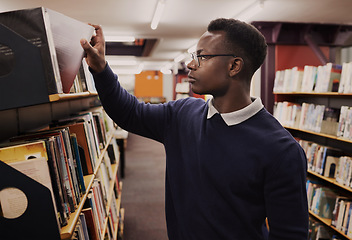 Image showing University, books and black man in a library reading and learning on campus for knowledge and education in college. Smart, clever and person doing research or studying by a shelf for an exam