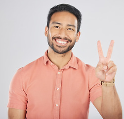 Image showing Portrait, smile and asian man with peace hands in studio for thank you, support or feedback on grey background. V, emoji and face of happy Japanese guy model with feedback, opinion or positive review