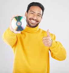 Image showing Man, portrait and CD with thumbs up and happy from music of DVD in studio. Smile, motivation and like emoji hand sign of a male person with white background and holding multimedia disk of audio