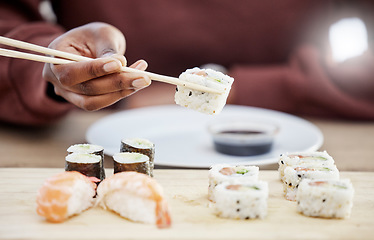 Image showing Sushi, seafood and restaurant with hands of person in store for brunch, Japanese cuisine and menu. Fish, salmon and health with closeup of customer eating for nutrition, Asian diet and fine dining