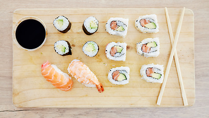 Image showing Sushi, top view and soy sauce with food on wood board, closeup with salmon and rice, healthy and luxury. Japanese cuisine, catering with lunch or dinner meal, chopsticks and seafood with nutrition