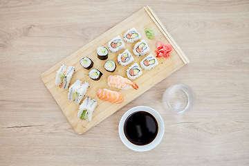 Image showing Sushi, top view and soy sauce with seafood on wood board, closeup with salmon and rice, healthy and luxury. Japanese cuisine, catering with lunch or dinner meal, chopsticks and food with nutrition