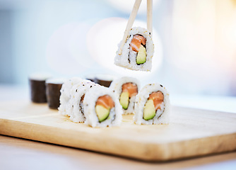 Image showing Sushi, food on wood board with fish and eating, salmon and rice with avocado, healthy and luxury. Japanese cuisine, catering with lunch or dinner meal, chopsticks and seafood, nutrition and gourmet