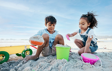 Image showing Boy, girl and shovel with bucket, beach sand and digging for playing, outdoor and vacation in summer. Kids, siblings and plastic toys for sandcastle, construction game and together on holiday by sea