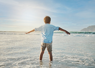 Image showing Freedom, fun and child in waves at beach, playful on tropical summer holiday in Australia with blue sky. Ocean, adventure and sun, back of boy in water and playing with energy on island vacation