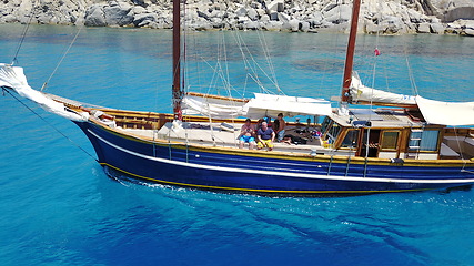 Image showing People on wooden boat, sailing in Greece and summer sun on ocean holiday, relax in freedom and nature. Yacht vacation, family travel and tropical cruise on sea adventure to Greek island on blue water