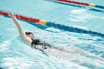 Image showing Sports, swimming pool and woman swimmer training for a race, competition or tournament. Fitness, workout and female athlete practicing back stroke cardio water skill for exercise, speed or endurance.