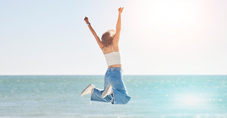 Image showing Happy woman, freedom and jump at beach with arms stretching for purpose, energy and motivation. Back view, success and fun at sea, summer vacation and sunshine travel, hope and wellness celebration