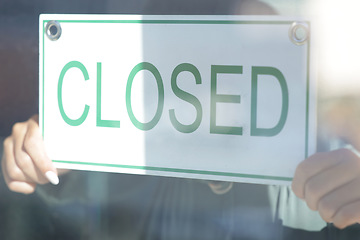 Image showing Closed, sign and window with a small business owner or entrepreneur hanging a signage notice behind closed. Management, store and retail with a woman employee in a shop to hang a poster on a door