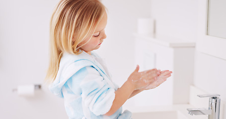 Image showing Girl washing her hands in the bathroom of her home for hygiene, stop germs and prevent bacteria. Healthcare, clean and young child doing sanitary routine with soap and water in the basin at her house