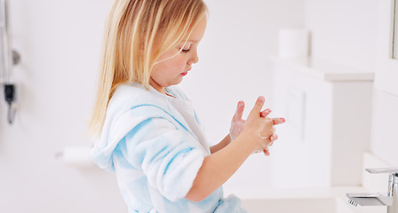 Image showing Girl washing her hands in the bathroom of her home for hygiene, stop germs and prevent bacteria. Healthcare, clean and young child doing sanitary routine with soap and water in the basin at her house