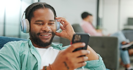 Image showing Headphones, relax and black man with a phone on a sofa in living room listening to music and chatting. Rest, chill and African guy streaming radio, album or playlist while relaxing on couch at home.