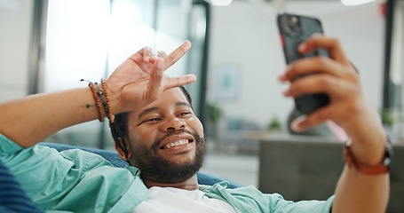 Image showing Black man, phone and peace sign on video call with smile for social, networking or communication at the office. African American man relaxing on break talking on smartphone videocall at the workplace