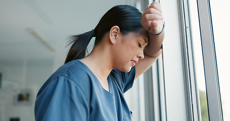 Image showing Healthcare nurse, stress and headache by window for working burnout, frustrated employee and tired asian woman in hospital. Doctor, pain and sad medical worker, anxiety or mental health depression