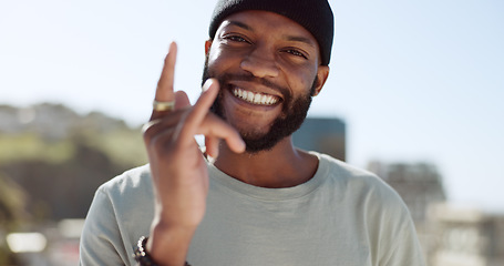 Image showing Hand, happy and sign with a black man showing a gesture while standing outdoor in the city with a smile on his face. Portrait, freedom and carefree with a young male gesturing or signing in a town