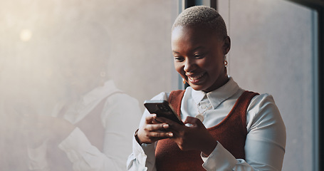 Image showing Happy, smile and face of a black woman on a phone while standing by the window in office. Technology, happiness and African female employee networking on social media or the internet on break at work