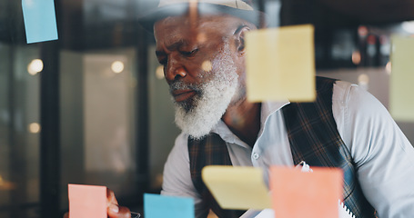 Image showing Strategy, planning and black man with sticky notes on glass wall brainstorming for new project. Development, motivation and small business startup at at night, man thinking and writing notes for idea