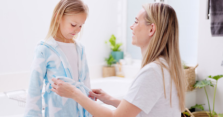 Image showing Girl, mother and bathrobe in a bathroom for cleaning, wellness and hygiene in their home together. Children, washing and woman help child with gown after shower, bond and relax while talking