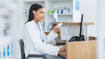 Image showing Young pharmacist working on computer at a pharmacy counter. Woman using technology to access drug database, does inventory checkup and dispensing online medicine prescriptions in a drugstore