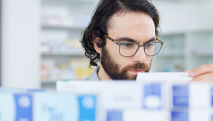 Image showing Man with glasses choosing medication on a shelf in a pharmacy. Customer with glasses browsing in aisle in a drugstore and finding what he needs before heading to the checkout with his vitamins