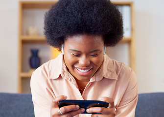 Image showing Woman playing a mobile game on her phone in landscape mode in the lounge at home. Excited young gamer smiling and laughing while enjoying some fun online entertainment in leisure with gaming apps