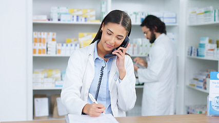 Image showing Pharmacist woman answering the telephone and giving advice to customer on flu shot treatment options in pharmacy. Chemist assisting remote client by checking medicine stock on their computer database