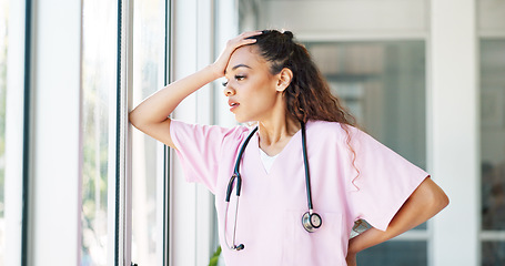 Image showing Doctor, woman and stress by window with headache, burnout or sad in hospital workplace with hand on head. Black woman, healthcare medic and mental health problem at clinic job with anxiety in Atlanta