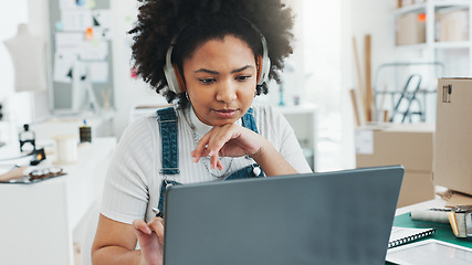 Image showing Black woman, laptop and notebook to study in office, home or studio to design. Woman, music and listening on headphones while learning online, with computer or pc at desk, in house or workplace