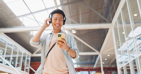 Image showing Asian man, phone and headphones for listening to music and dancing while walking in creative office with smile, happiness and positive mindset. Male entrepreneur during travel with network connection