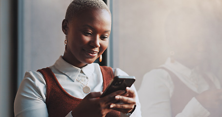 Image showing Black woman, business and typing on phone at window in office building for social networking connection, mobile app and reading notification. Happy worker, smartphone and search media on digital tech