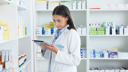 Image showing A young female pharmacist stocktaking in a dispensary using a tablet. Doctor preparing prescriptions and medication at clinic or pharmacy. Healthcare professional sorting medicine with digital device