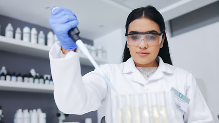 Image showing Female scientist experimenting with test tubes and a syringe. One young biologist or chemist putting blue liquid in glassware for medicinal research testing at an innovative research lab or clinic