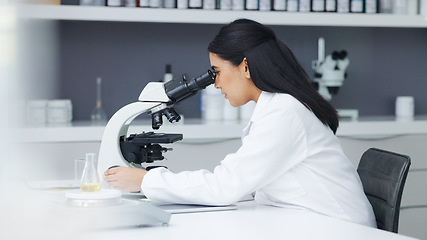 Image showing Young scientist using a digital tablet and microscope in a lab. Female pathologist analyzing medical samples while doing experiments to develop a cure. Microbiologist conducting forensic research