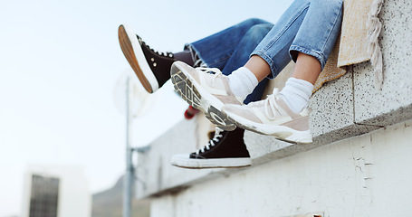 Image showing Shoes, legs and couple on rooftop in the city sitting together, have fun and bonding. Fashion sneakers, style and friends kick feet on building edge, enjoy weekend, freedom and holiday in urban town