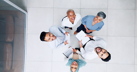 Image showing Collaboration, overhead and huddle with a business team laughing while working together in an office. Face, teamwork and documents with a man and woman employee group standing in a circle from above